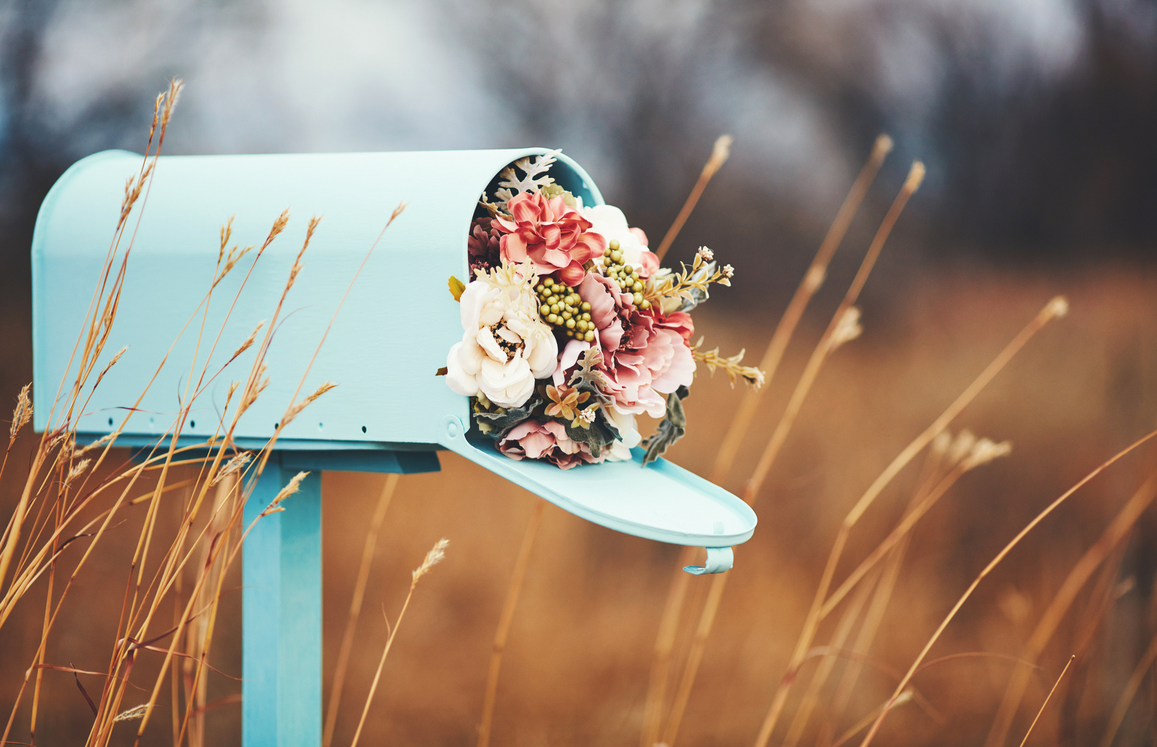 Pastel teal mailbox with bouquet of flowers